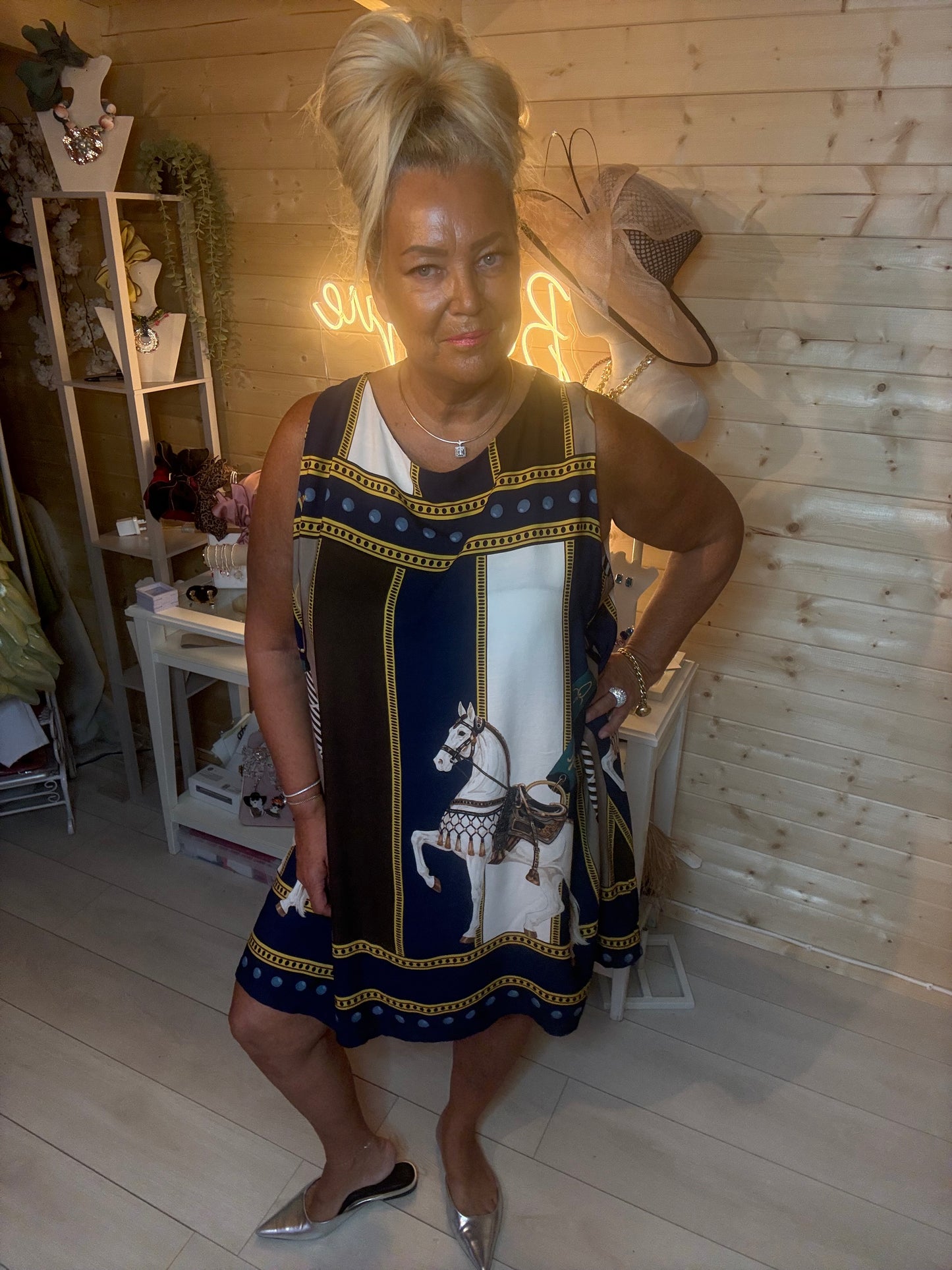 Navy equestrian scarf print shift dress – full length front view showing horse and chain panel design with gold border trim, styled with silver mules in boutique setting
