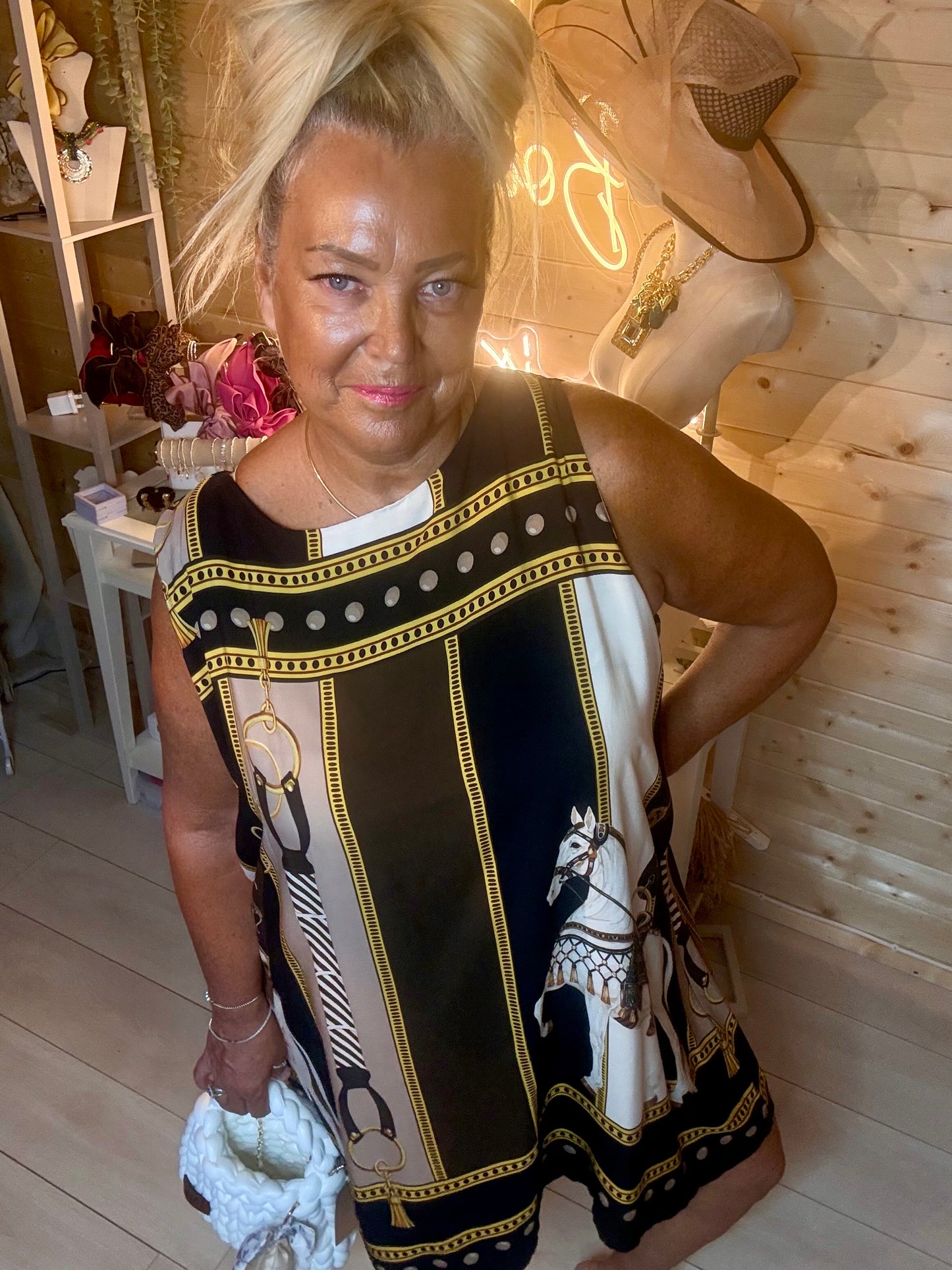 Brown equestrian scarf shift dress – close up three quarter view showing horse and chain print detail, round neckline and gold border trim