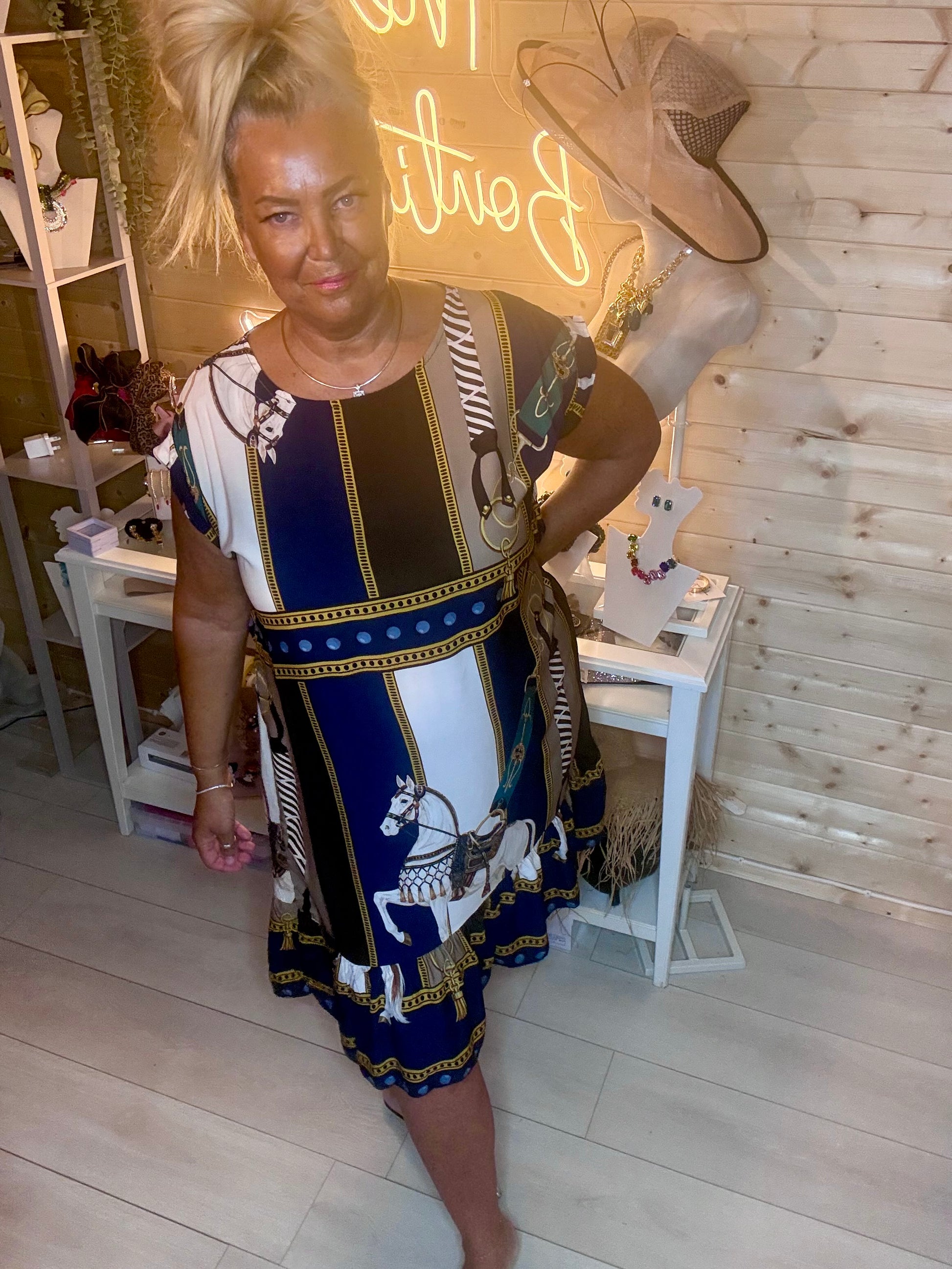 Equestrian scarf print dress – full length front view showing relaxed cap sleeve silhouette and beautiful navy, white and gold horse print with tiered ruffle hem and silver mules