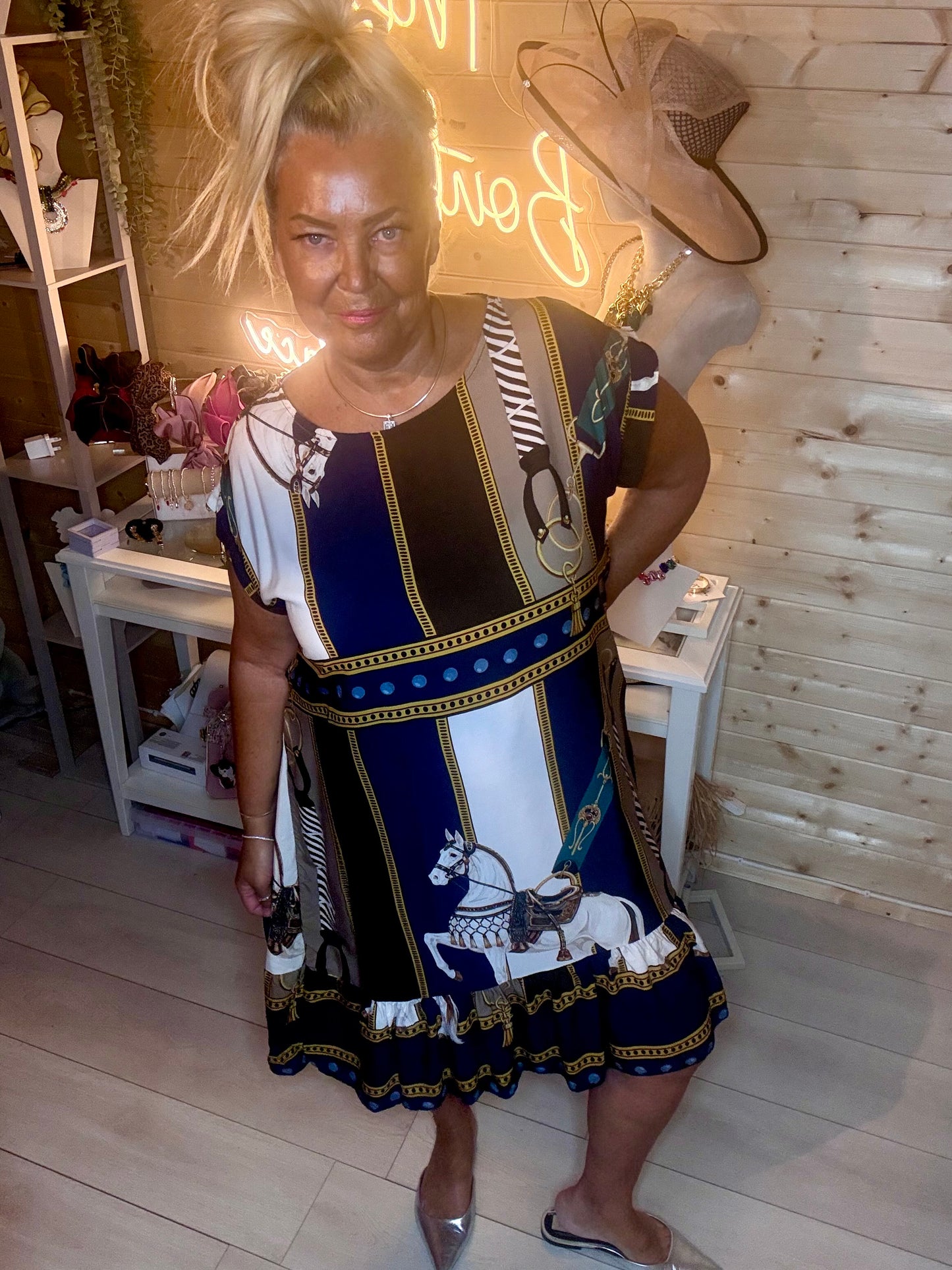 Navy equestrian print shift dress – full length boutique shot showing panelled scarf print with horse motif, gold chain detail and floaty tiered ruffle hem styled with silver mules
