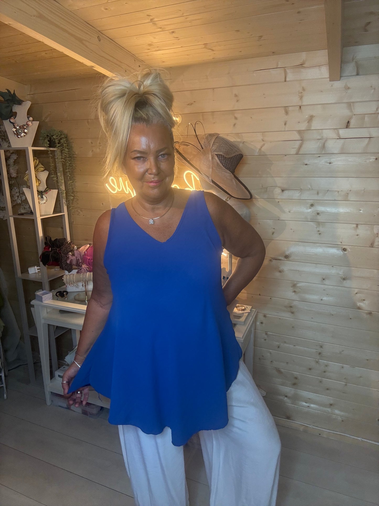Royal blue swing vest top – three quarter length boutique shot showing curved asymmetric hem and relaxed silhouette with white trousers