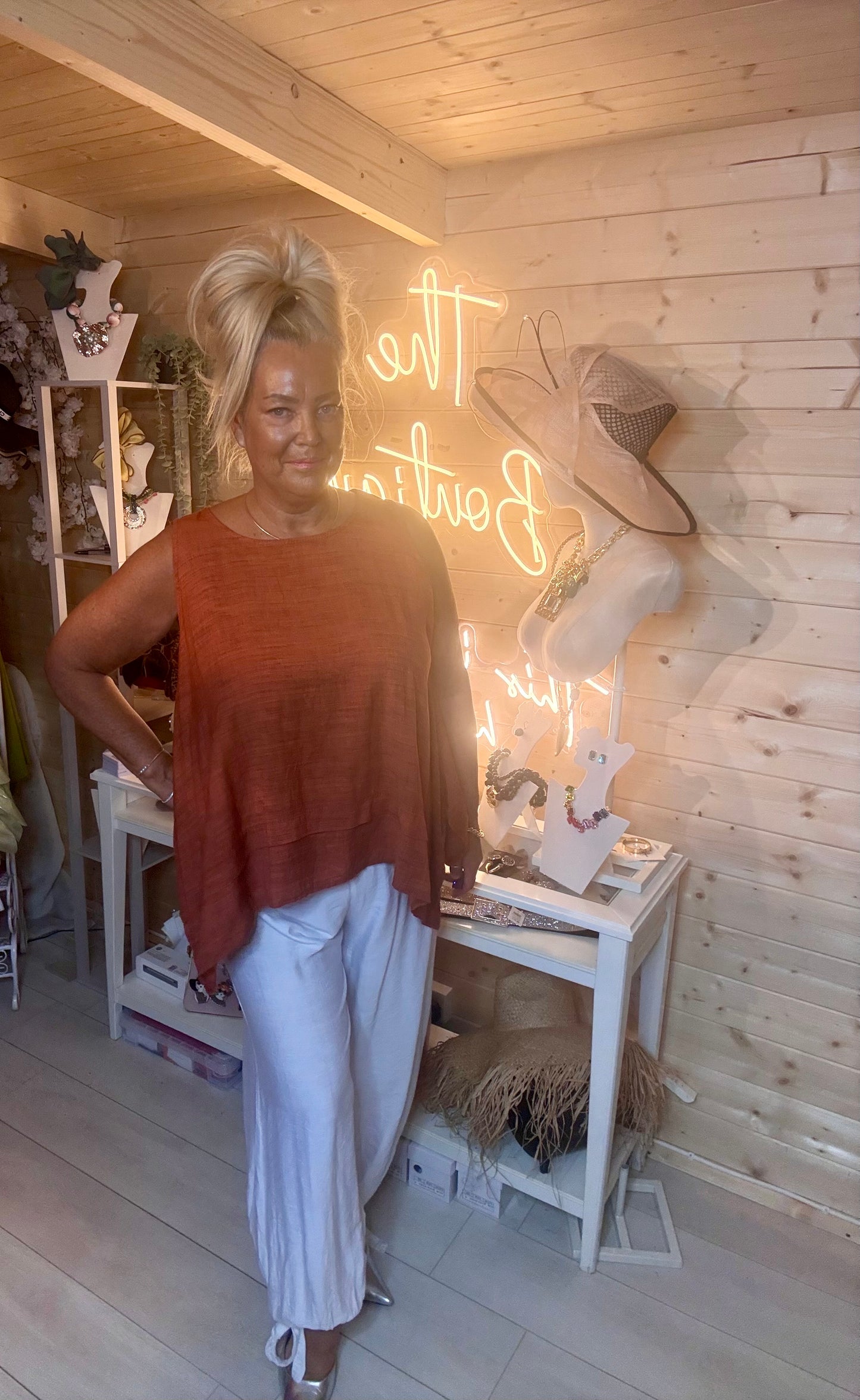 Rust fine knit swing top – three quarter length boutique shot showing relaxed swing silhouette and layered hem detail with white trousers