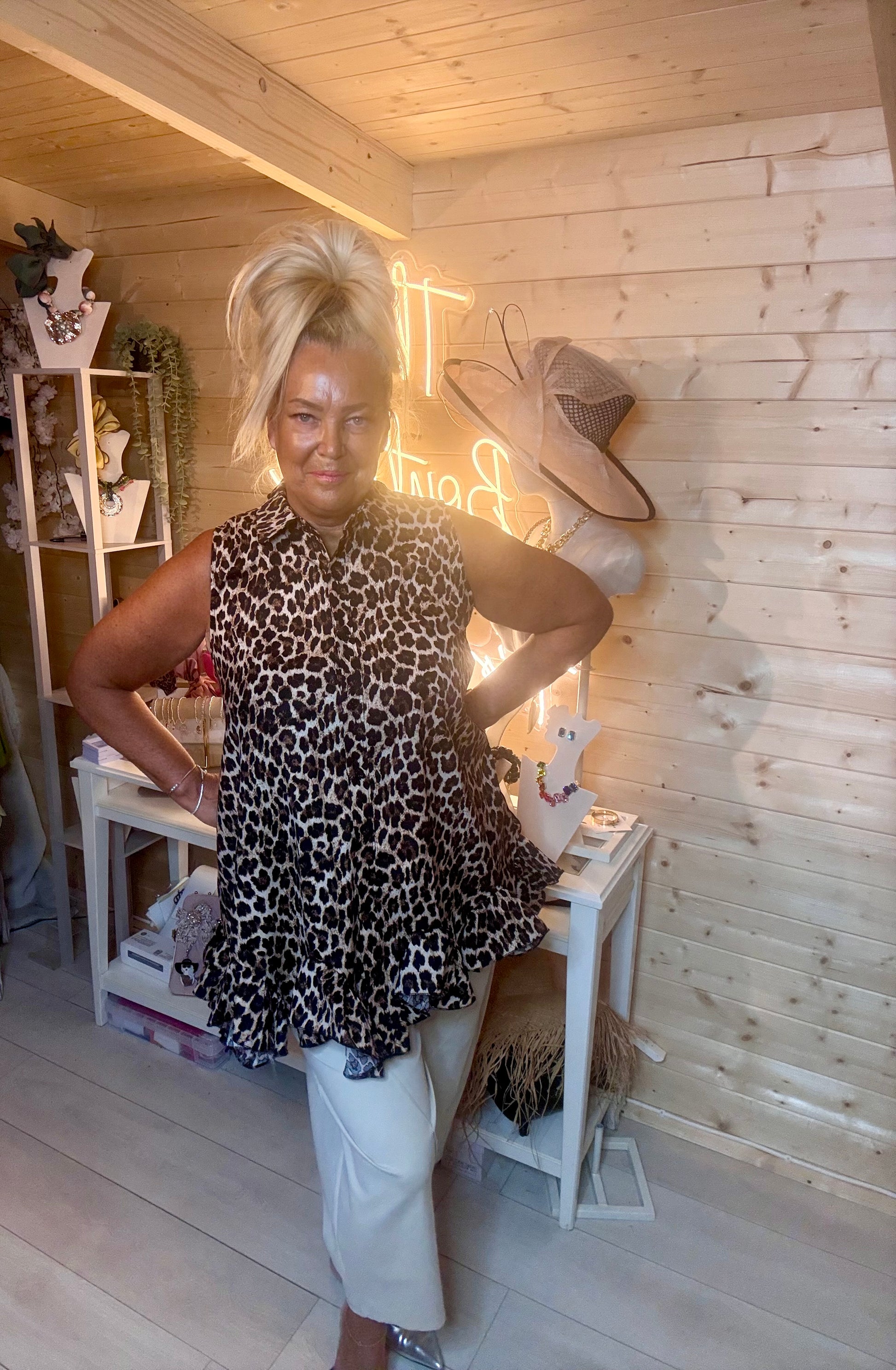 Leopard print ruffle hem tunic – full length three quarter view showing floaty swing silhouette and tiered peplum frill with white trousers and silver mules