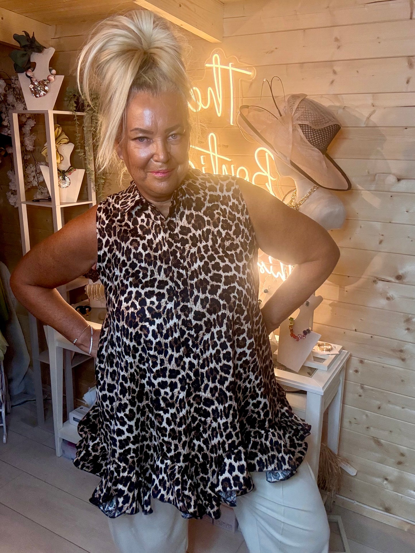 Leopard print sleeveless swing top – full length side view showing tiered ruffle hem and relaxed swing silhouette styled with white wide-leg trousers