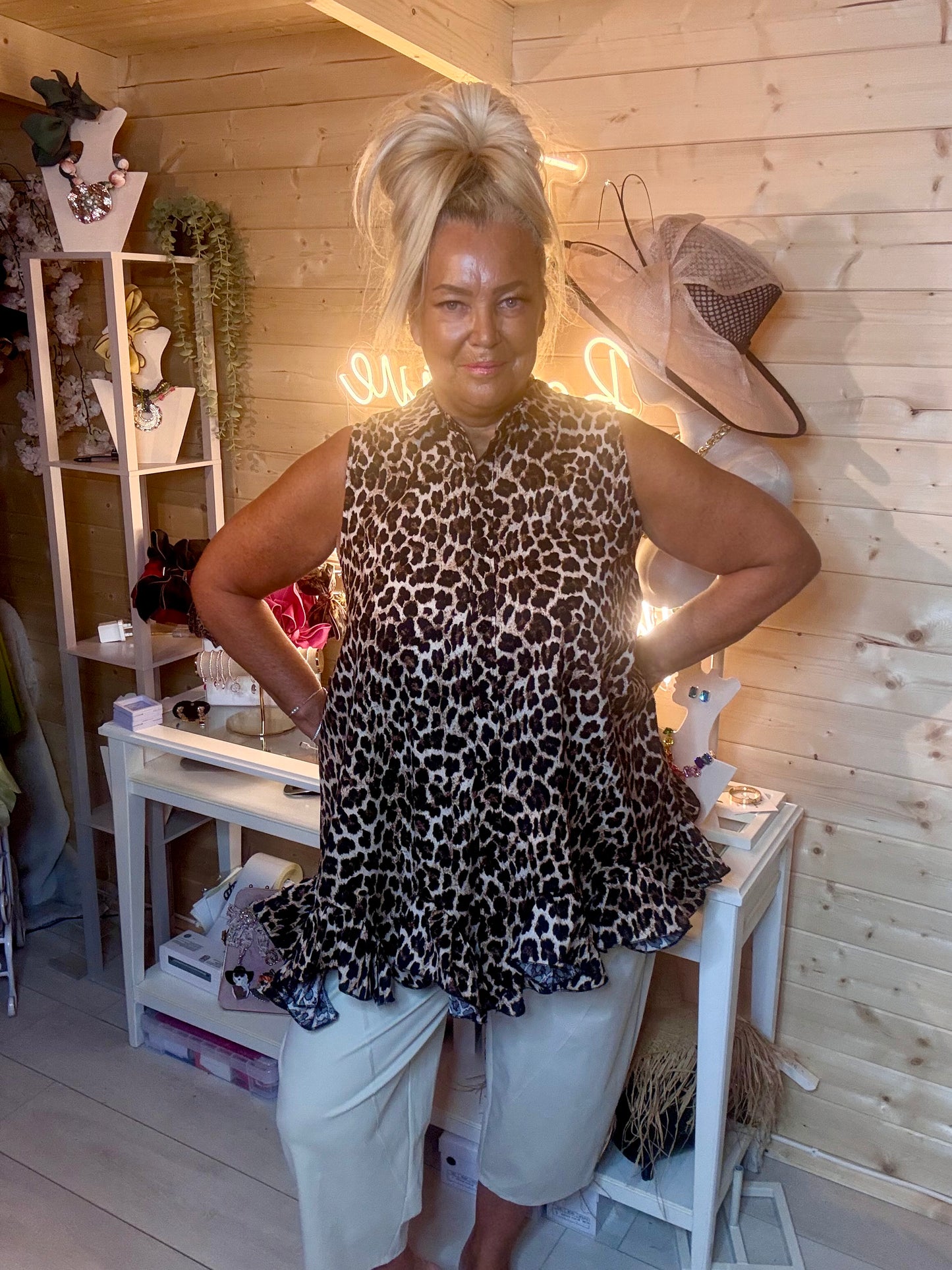 Leopard print tunic top – full length front view showing shirt collar, sleeveless design and peplum ruffle hem detail styled with white shorts and silver mules