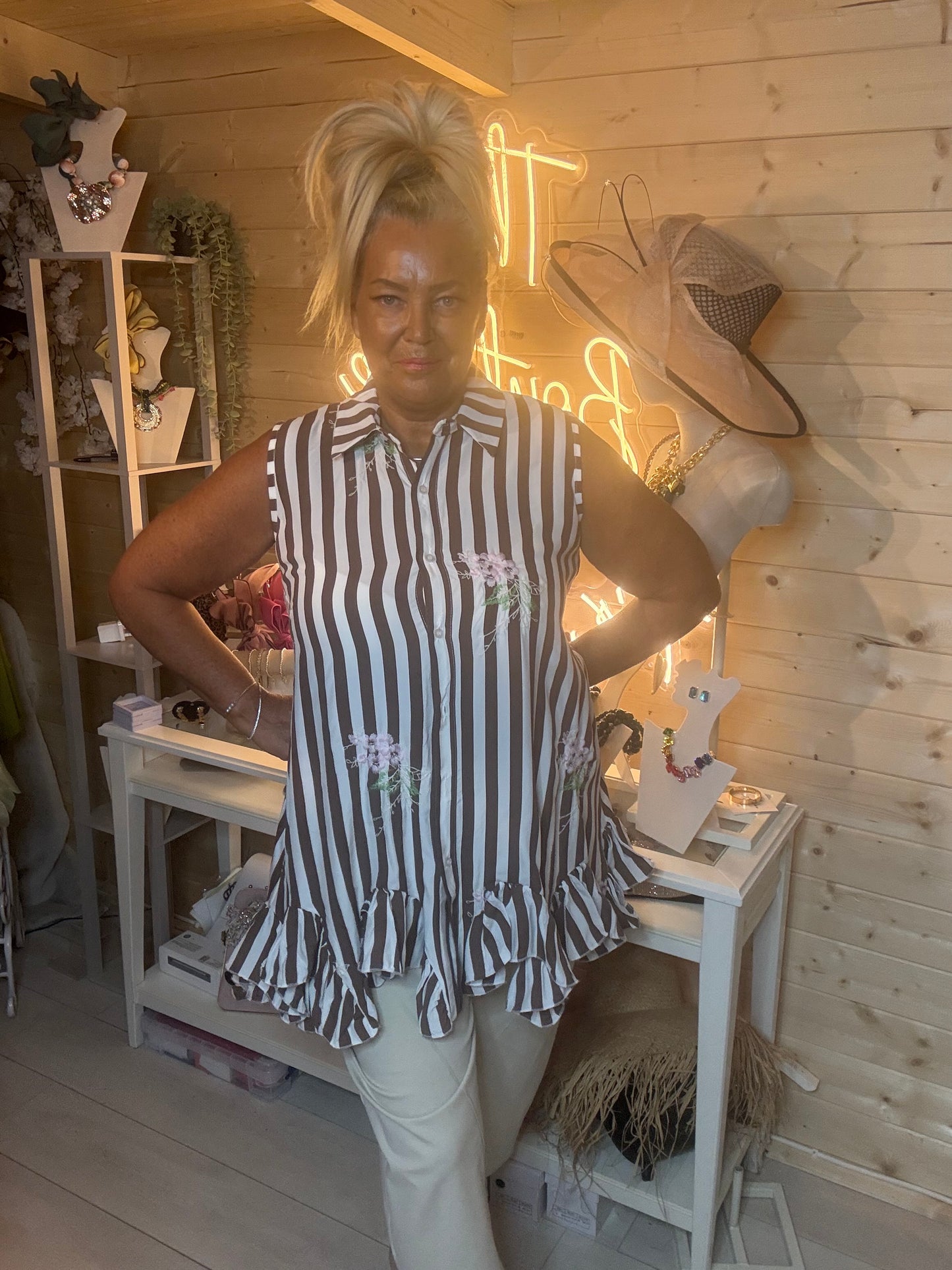 Navy stripe sleeveless shirt tunic – full length side view showing double ruffle peplum hem and relaxed swing silhouette styled with stone shorts in boutique setting