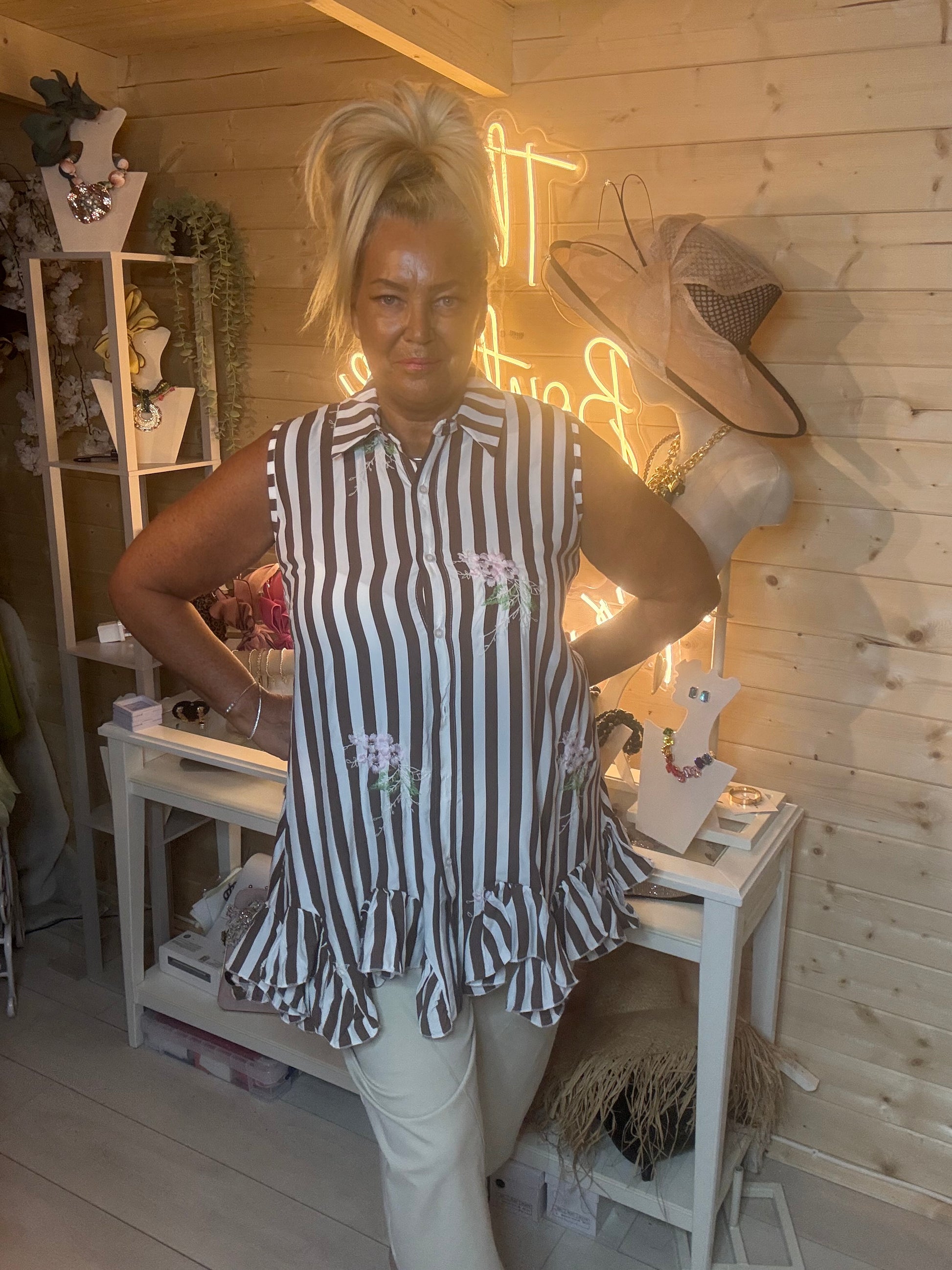 Navy stripe sleeveless shirt tunic – full length side view showing double ruffle peplum hem and relaxed swing silhouette styled with stone shorts in boutique setting