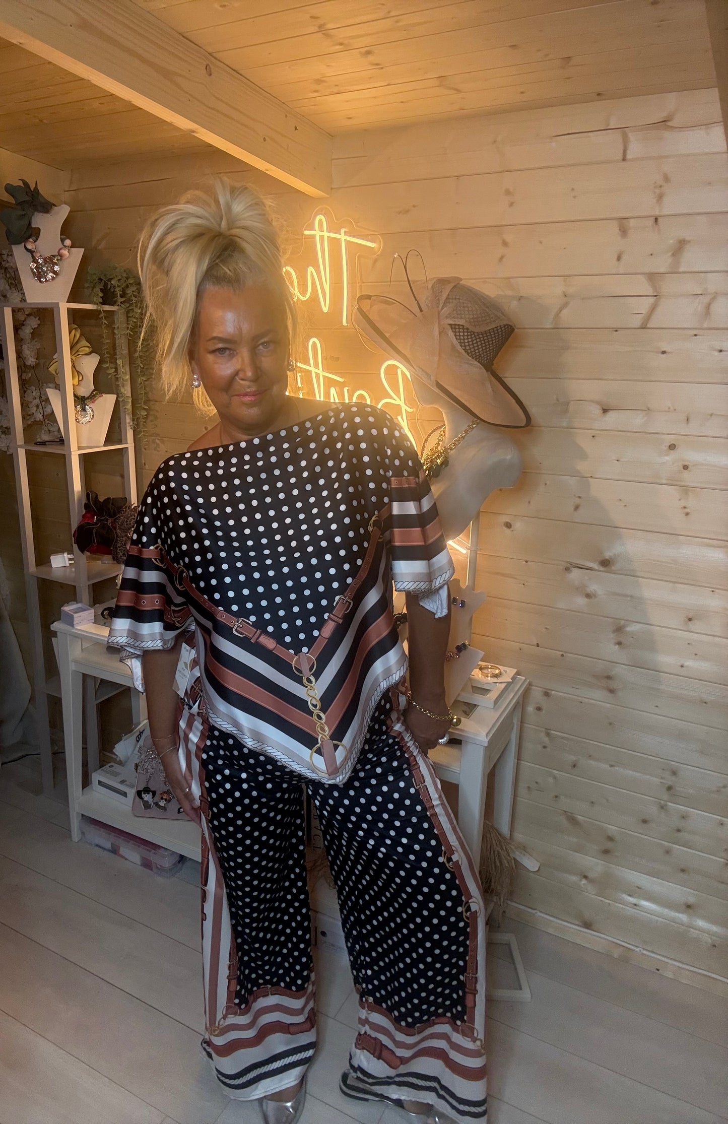 Rust polka dot co-ord set – full length three quarter view showing relaxed batwing top silhouette and wide-leg trousers with stripe border hem and silver mules