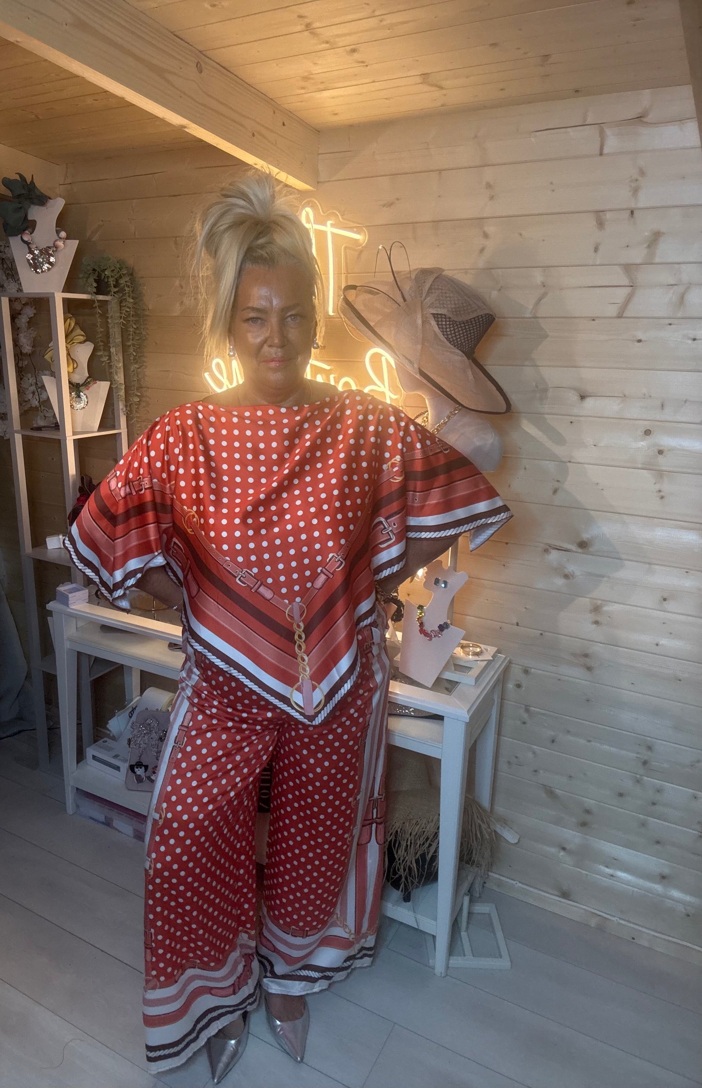 Rust polka dot scarf print co-ord – full length side view showing batwing sleeve detail and wide-leg trouser silhouette with silver mules in boutique setting