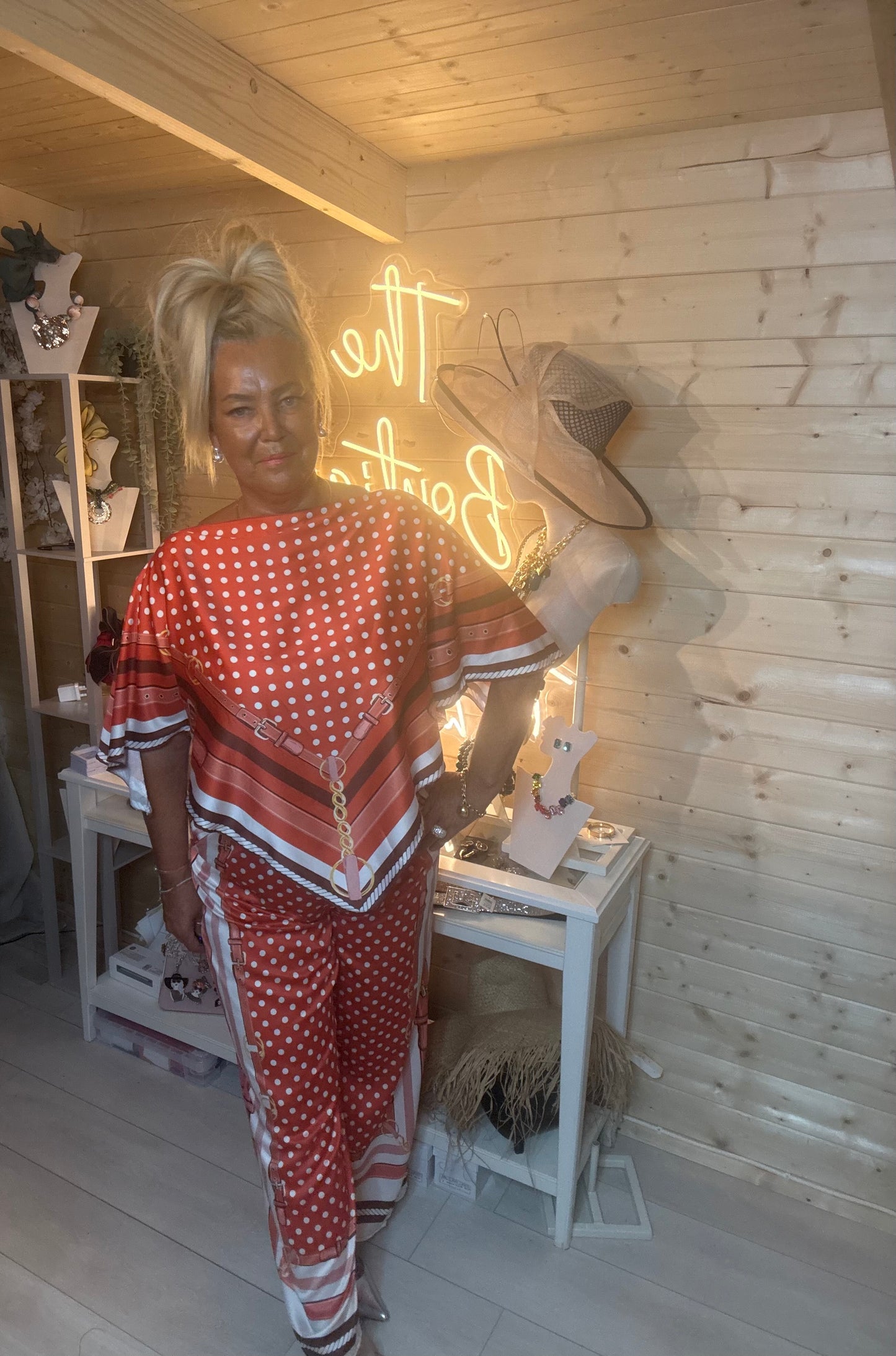 Rust polka dot co-ord set – close up three quarter view showing batwing top with chain and buckle scarf-print hem detail and wide-leg trouser waistband