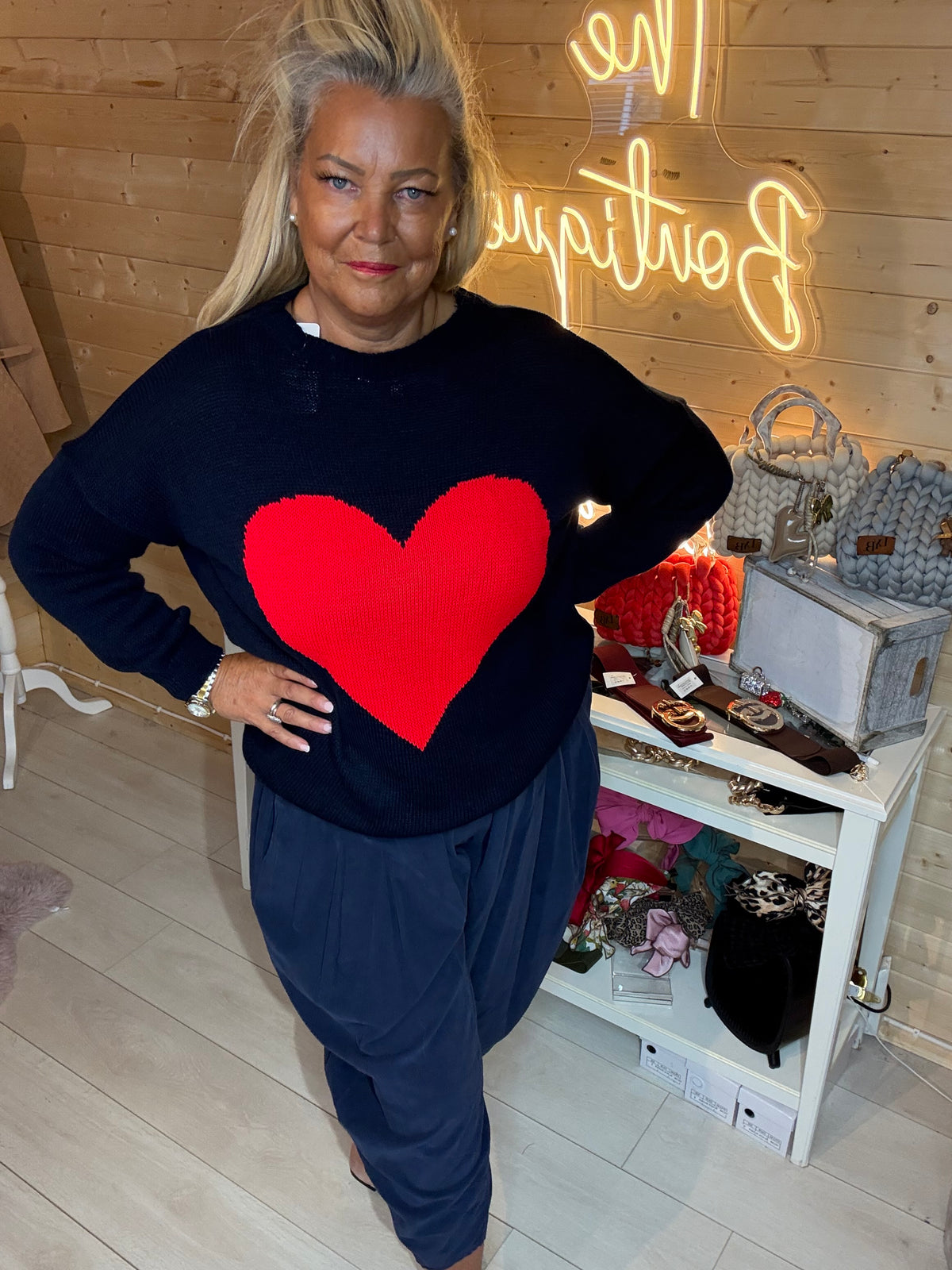 Front view of a navy jumper with a bold red heart, paired with navy trousers