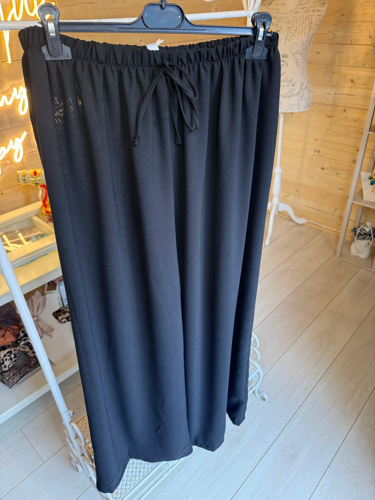 Noli Black wide-leg trousers on a hanger showing gathered elasticated waist