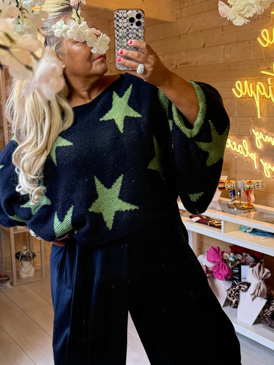 Close-up of Vega navy star knit jumper showing green stars, wide neckline and green sleeve edging