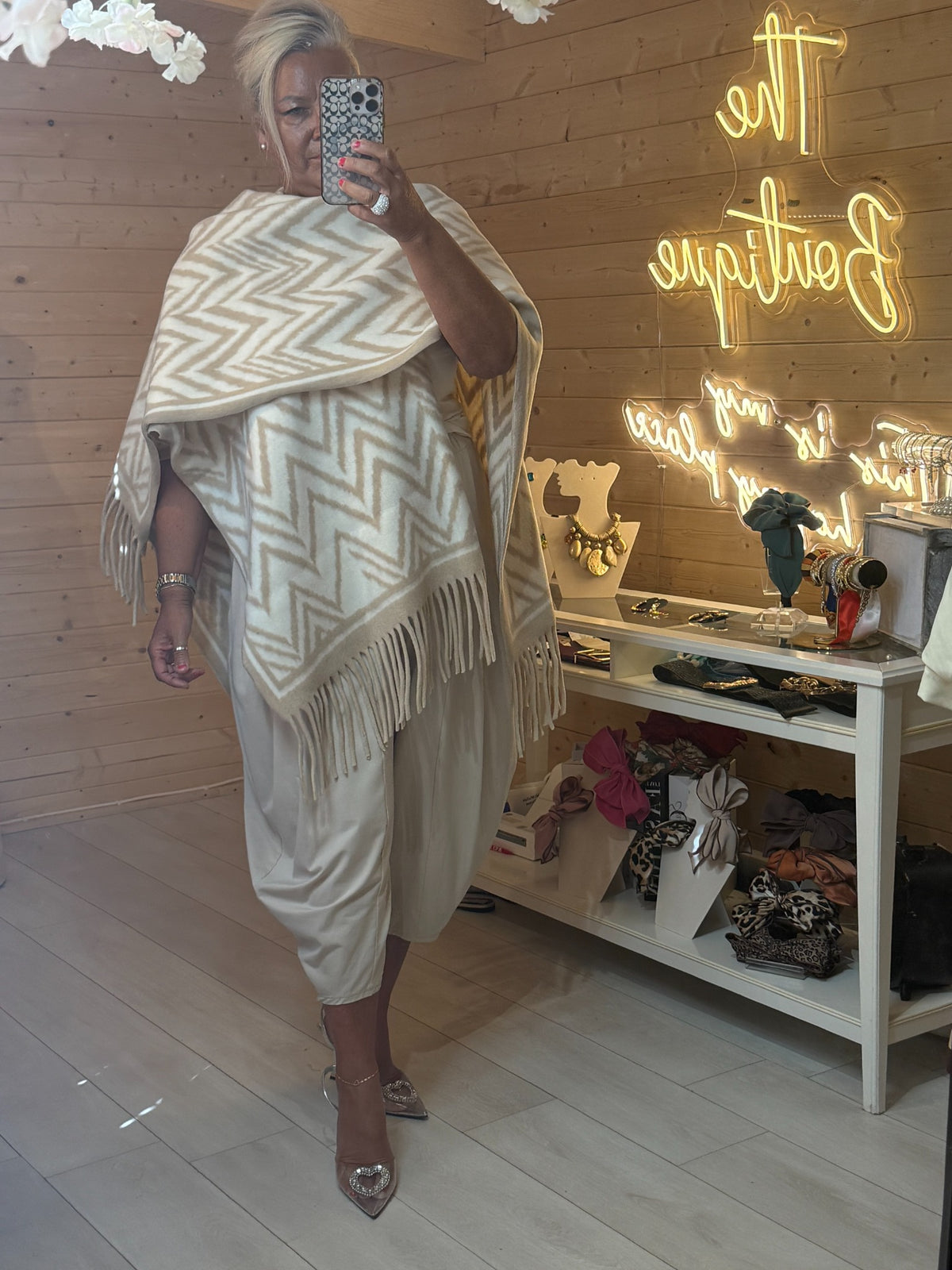 Cream white zigzag patterned Alba cape draped over the shoulder, worn with pale trousers