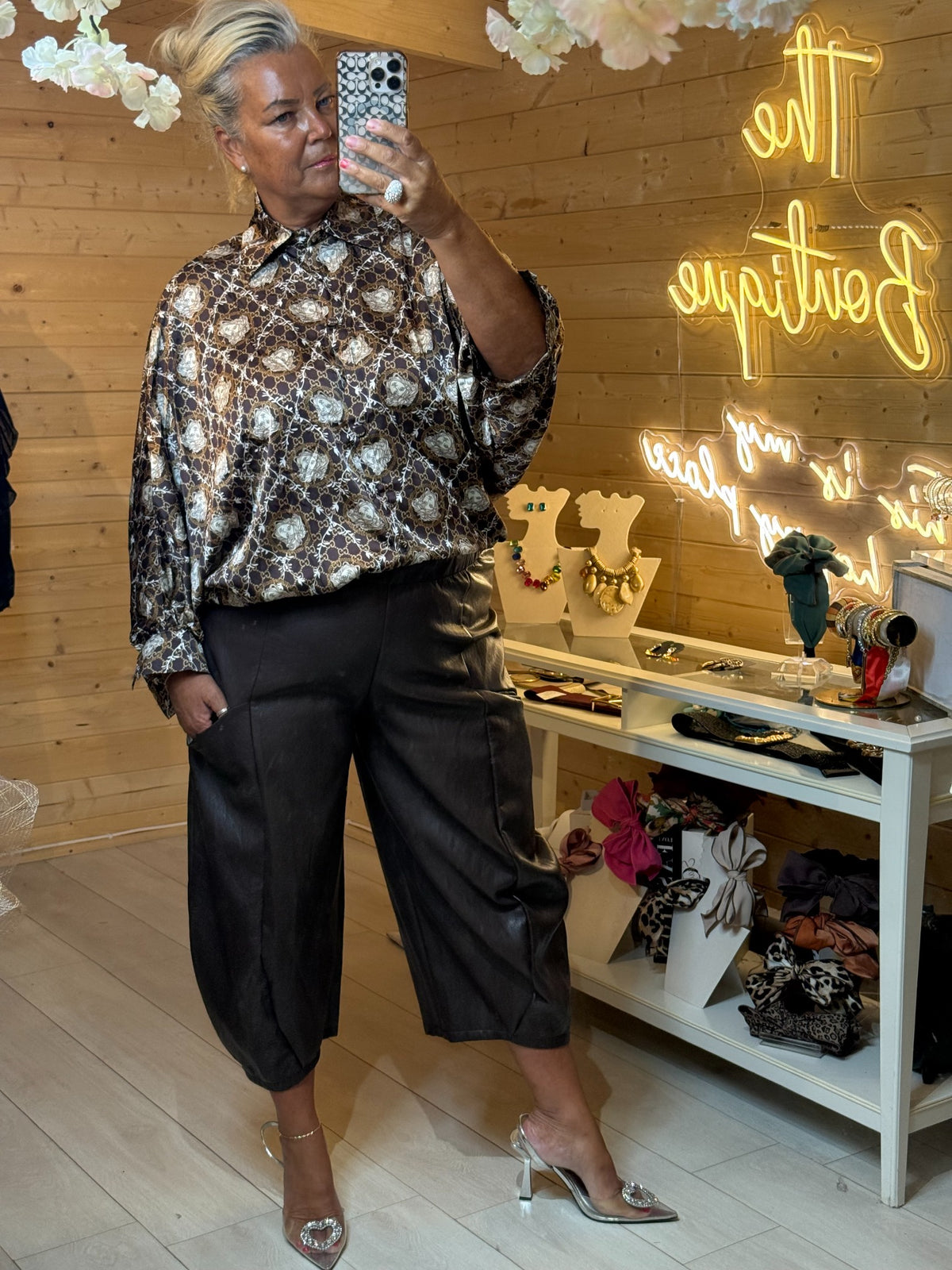 Black leatherette cropped barrel-leg trousers styled with a printed blouse and heels