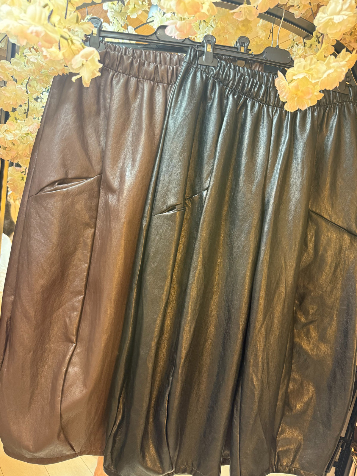 Brown and black leatherette barrel-leg trousers with elasticated waistbands displayed side by side