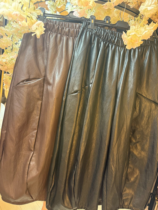 Brown and black leatherette barrel-leg trousers with elasticated waistbands displayed side by side