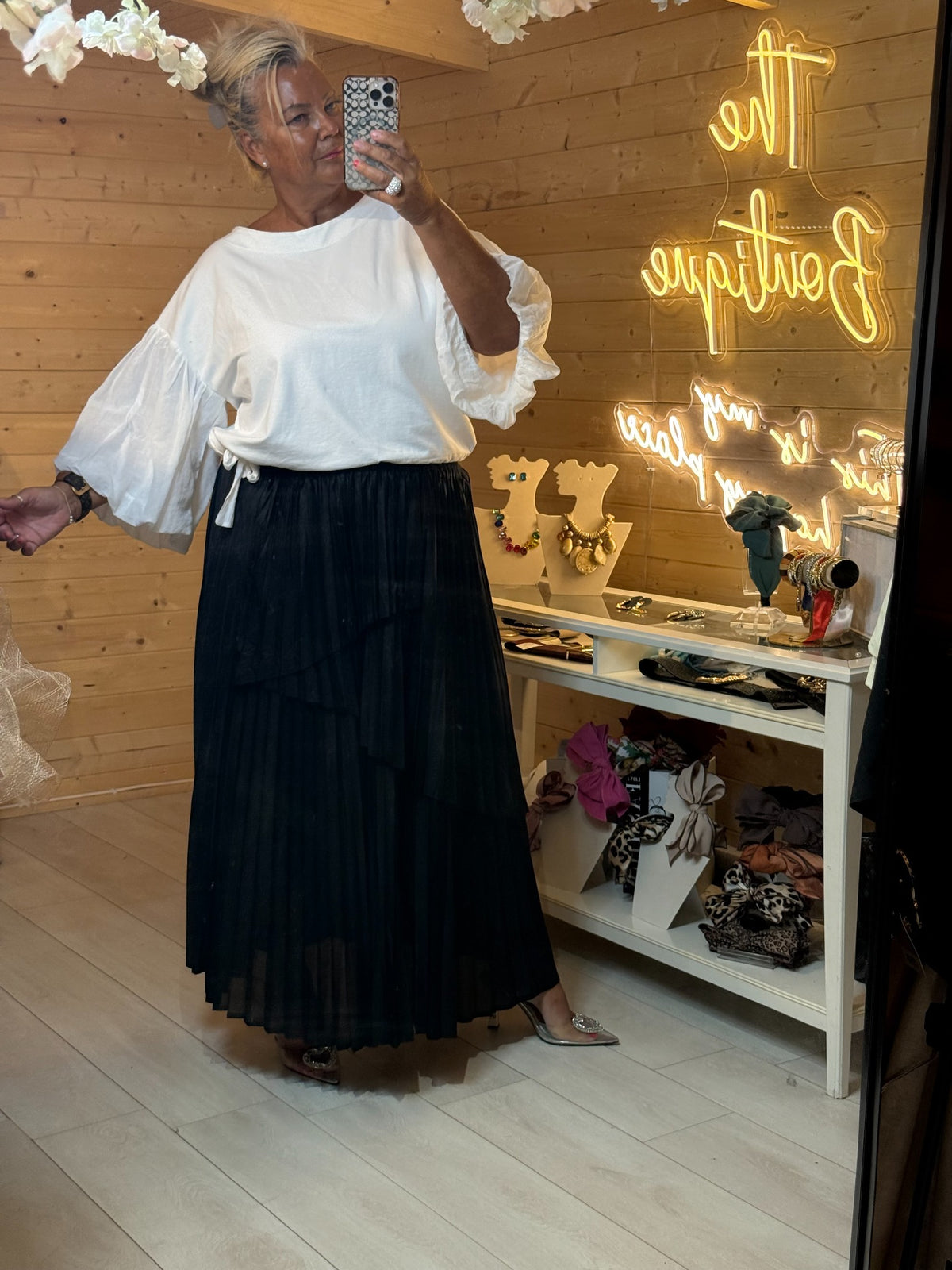 White relaxed-fit top with large puff sleeves styled with a black pleated maxi skirt