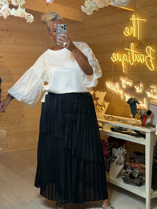 Black tiered pleated maxi skirt with asymmetric layered panels styled with white balloon sleeve top