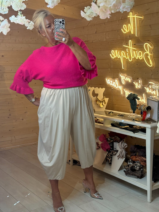 Talia bright hot pink knit jumper with ruffled three quarter sleeves styled with cream trousers