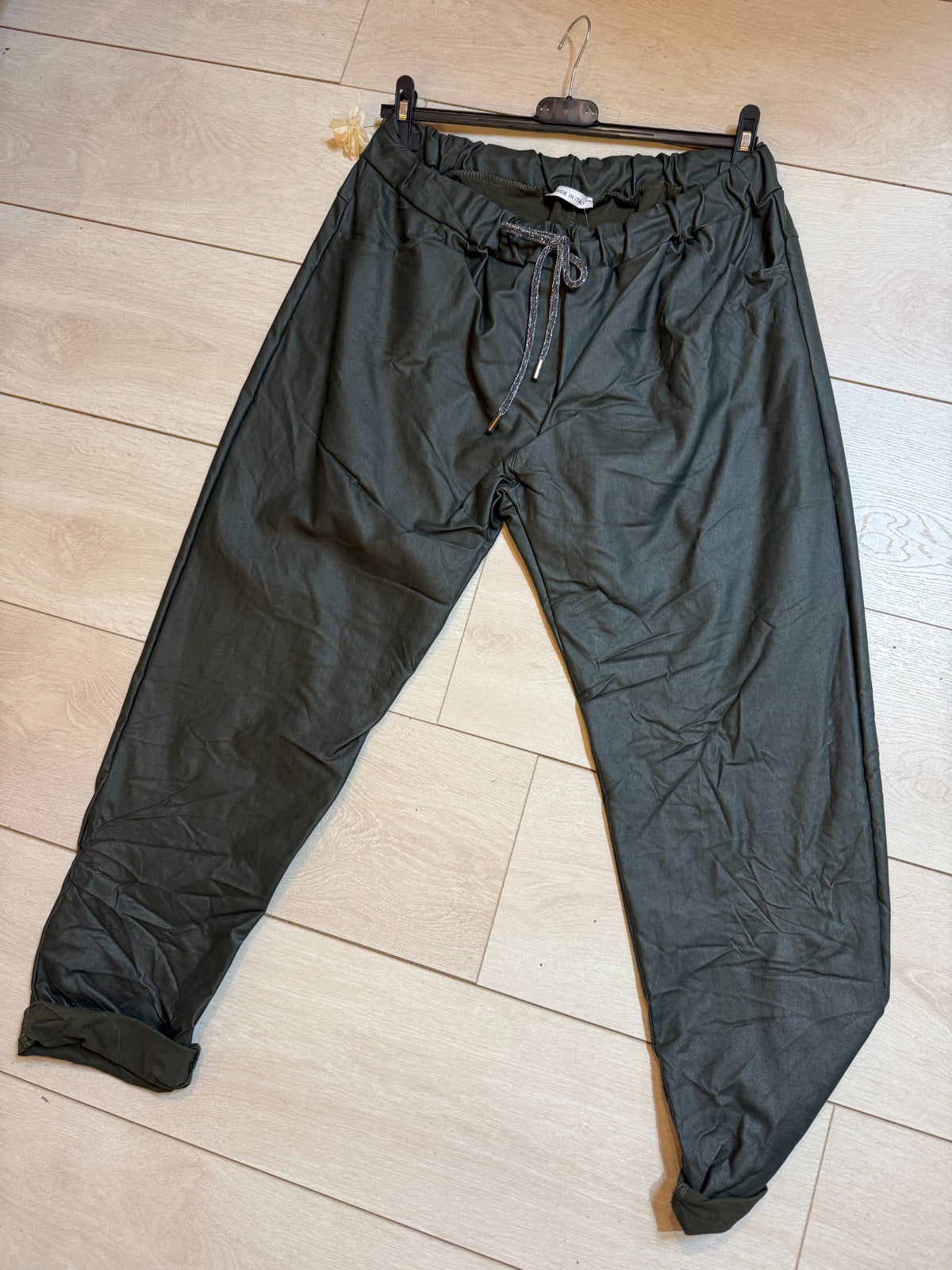 Khaki PU coated magic trousers with elasticated drawstring waist and turn-up cuffs laid flat